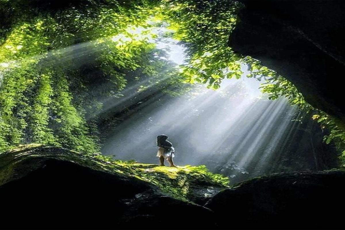 una persona in piedi nel mezzo di una grotta con il sole che splende