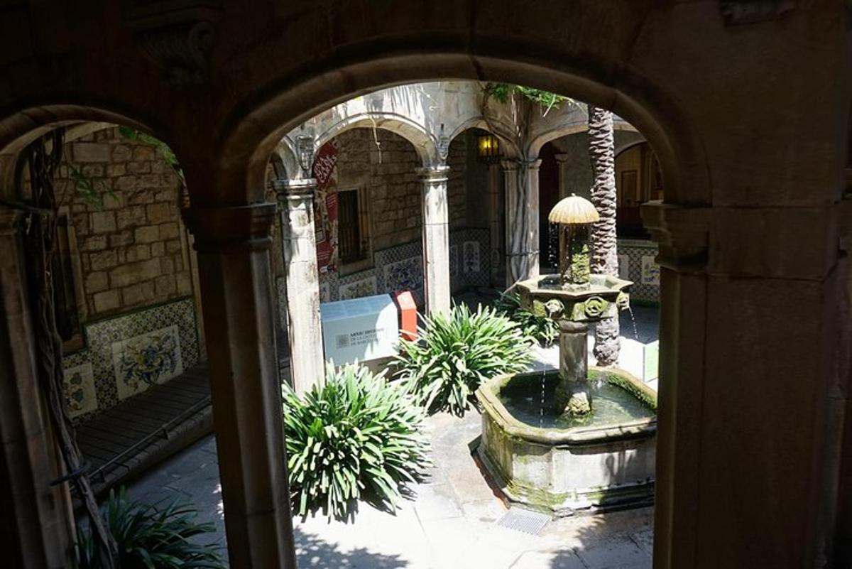 un arc amb una font en un pati amb plantes