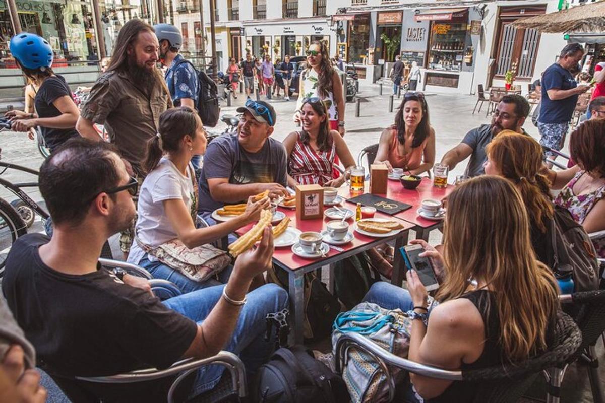 bir masanın etrafında oturup yemek yiyen bir grup insan