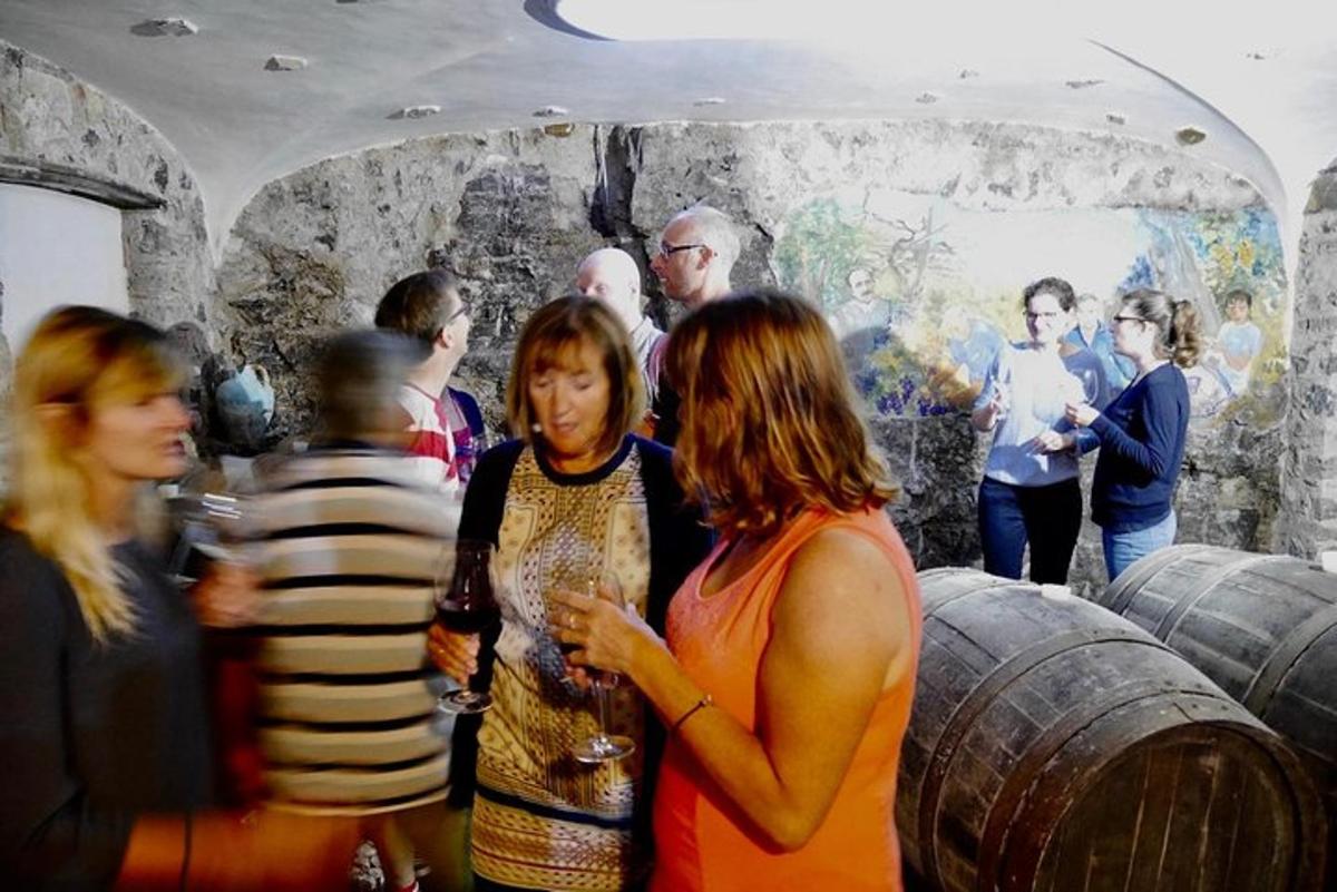 un gruppo di persone in piedi intorno a una stanza con botti di vino