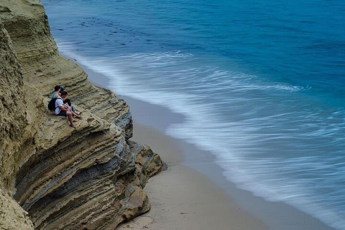 un homme assis sur une falaise à côté de la plage
