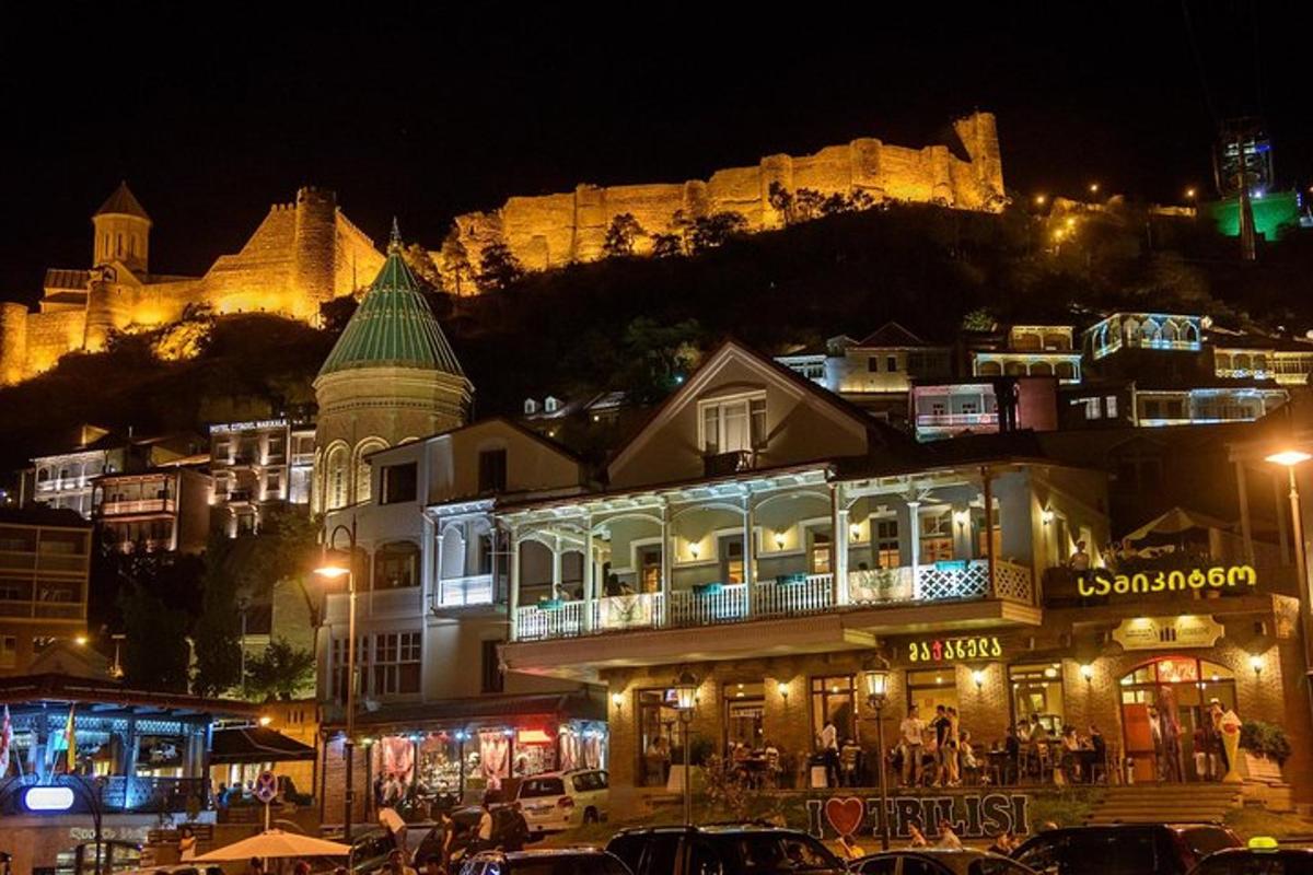 uma cidade à noite com um castelo ao fundo