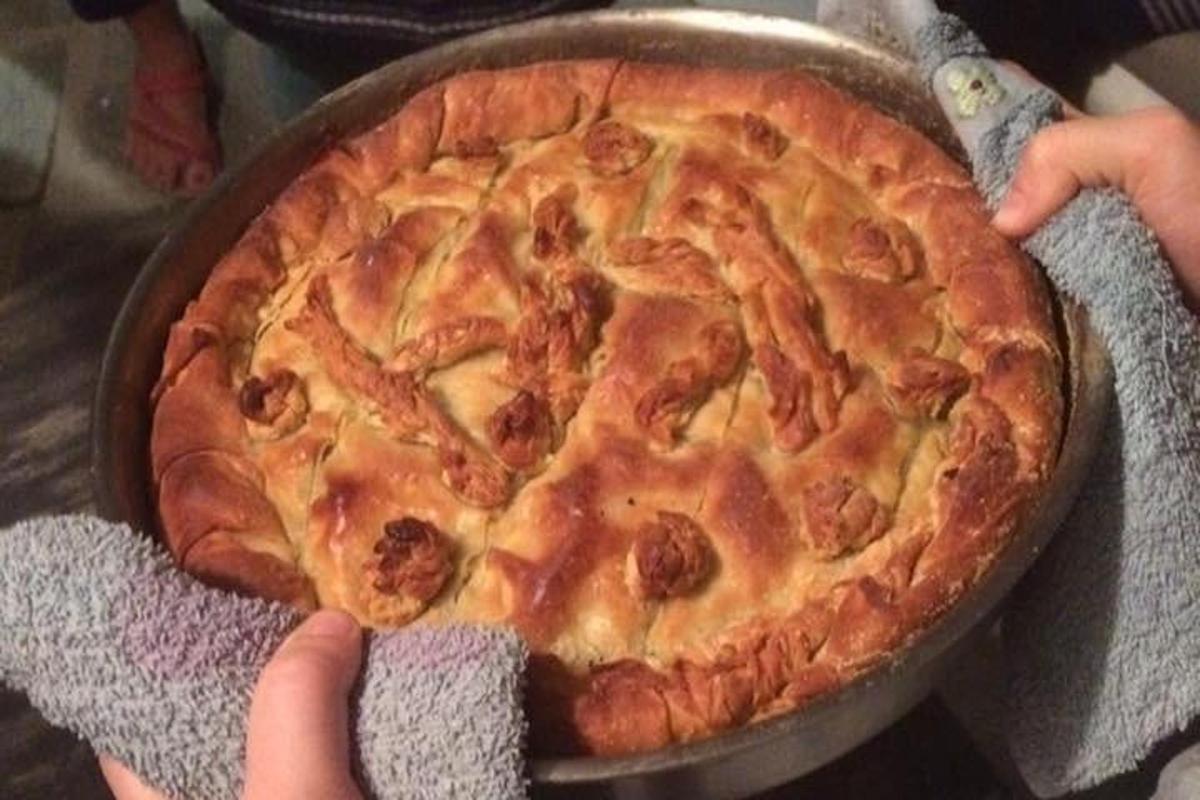 uma pessoa segurando uma pizza em uma panela