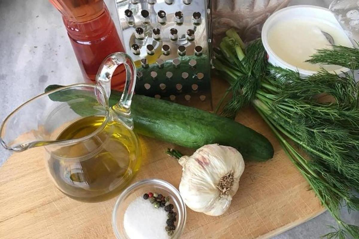 uma tábua de corte com um pepino verde e uma xícara de chá
