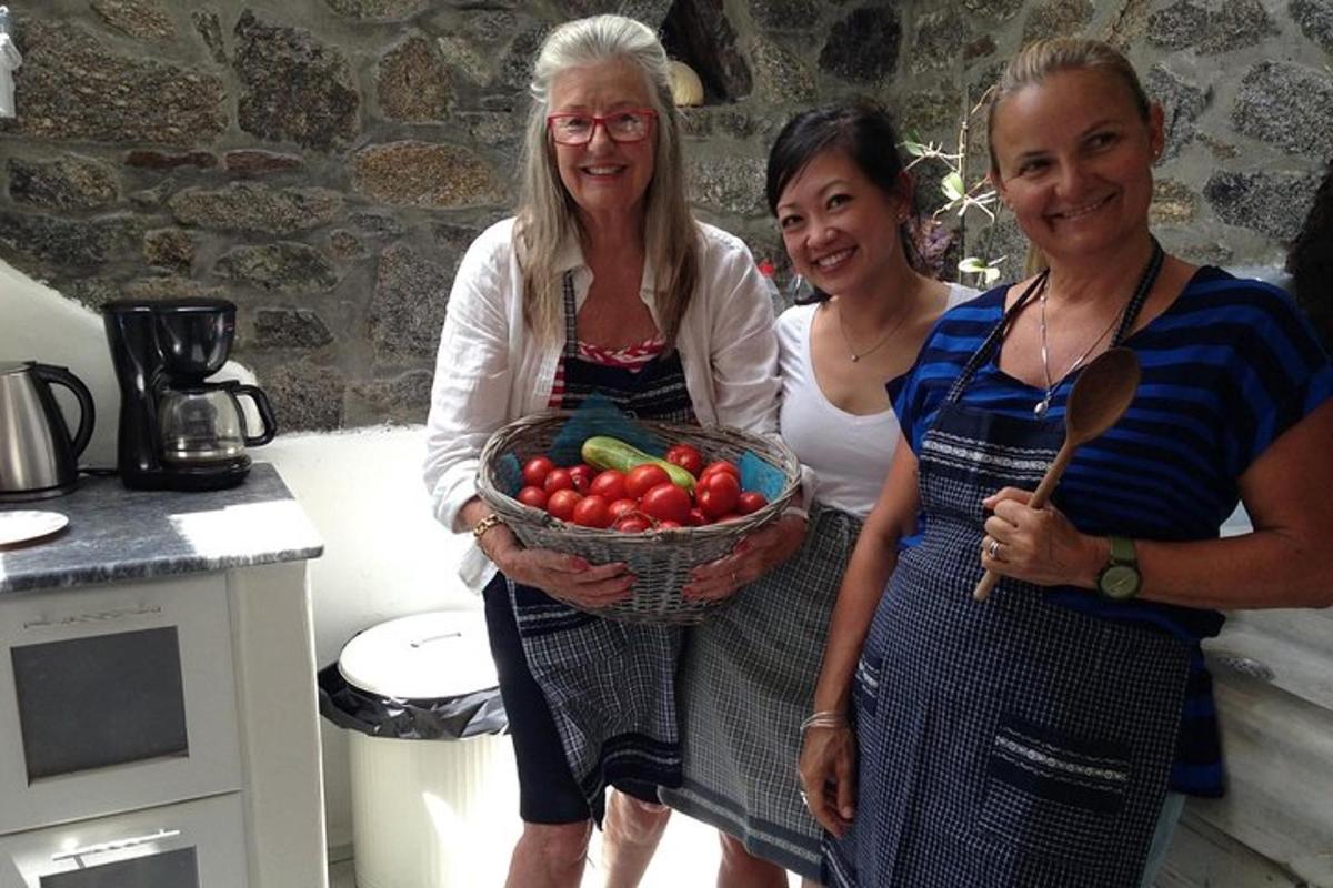 drei Frauen stehen in einer Küche und halten einen Korb mit Tomaten