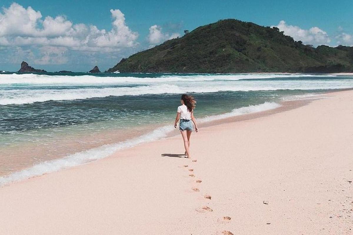 a woman walking on a beach with footprints in the sand