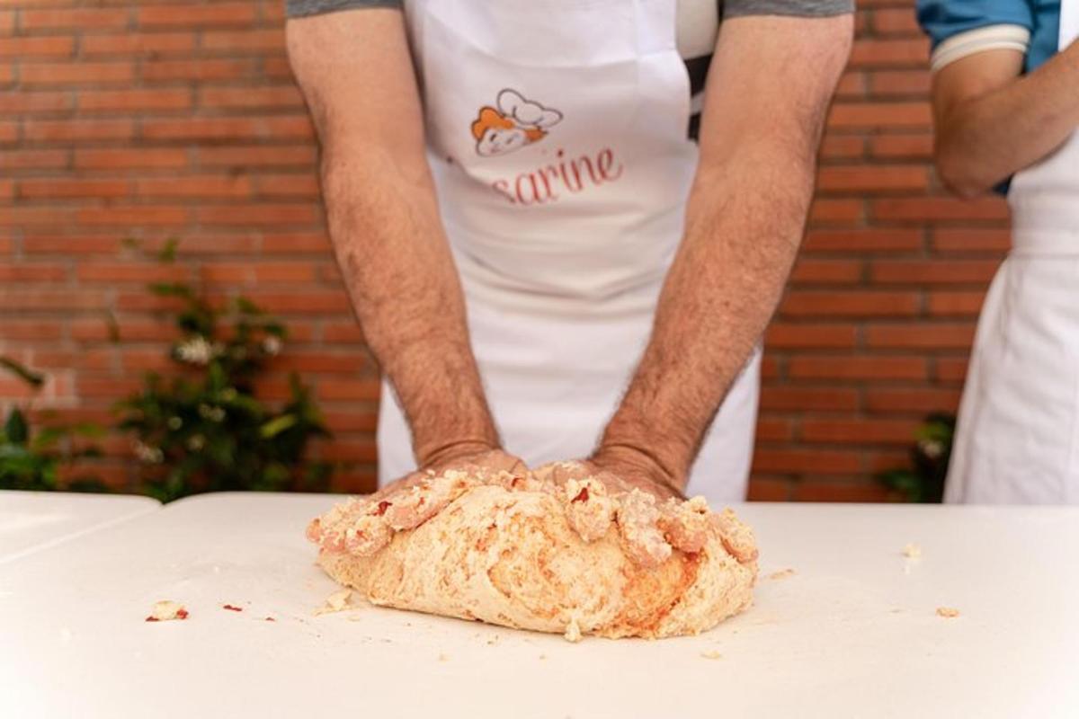 Un hombre con delantal sosteniendo un trozo de pan sobre una mesa.