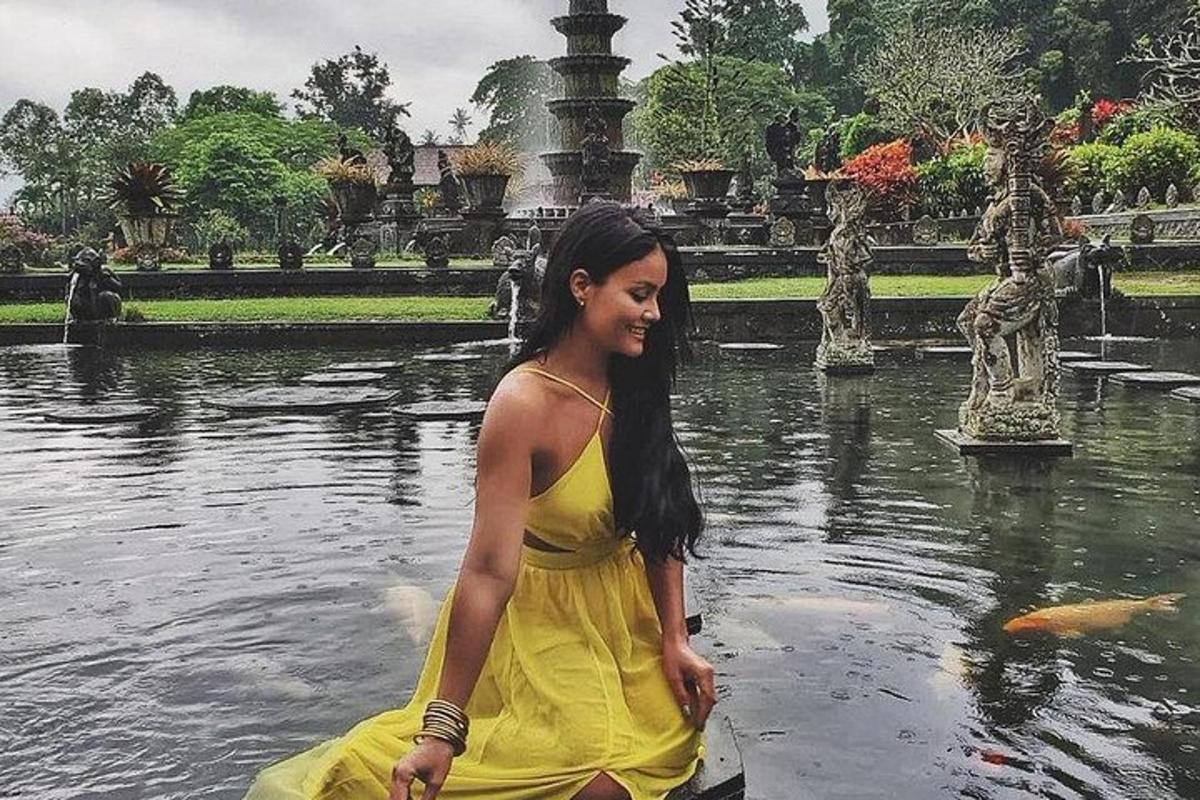 una donna in un vestito giallo in piedi in una fontana