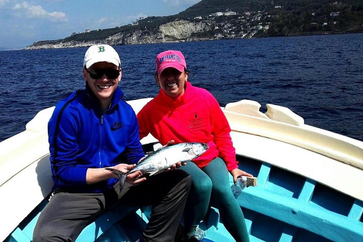 Dos personas sentadas en un bote sosteniendo un pescado