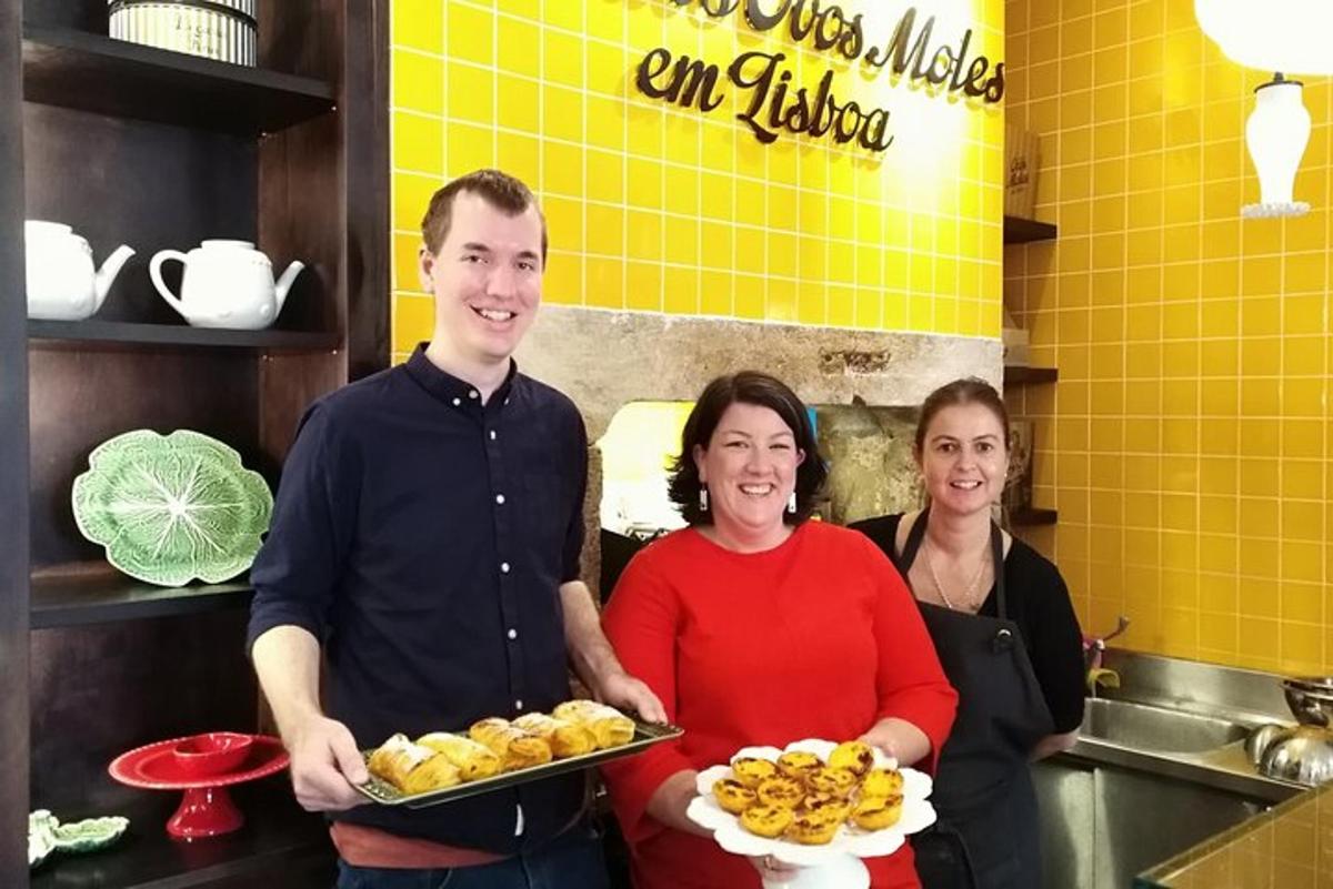 Un hombre y dos mujeres de pie en una cocina con platos de comida.