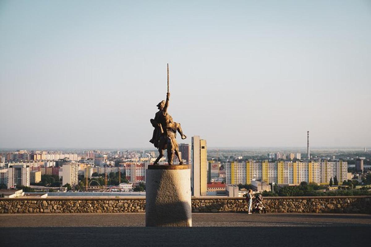 una statua in cima a un edificio con una città sullo sfondo