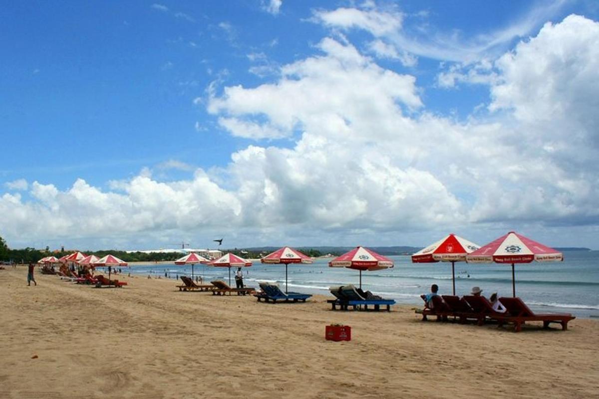 plaža z rdečimi in belimi senčniki ter ljudmi na plaži