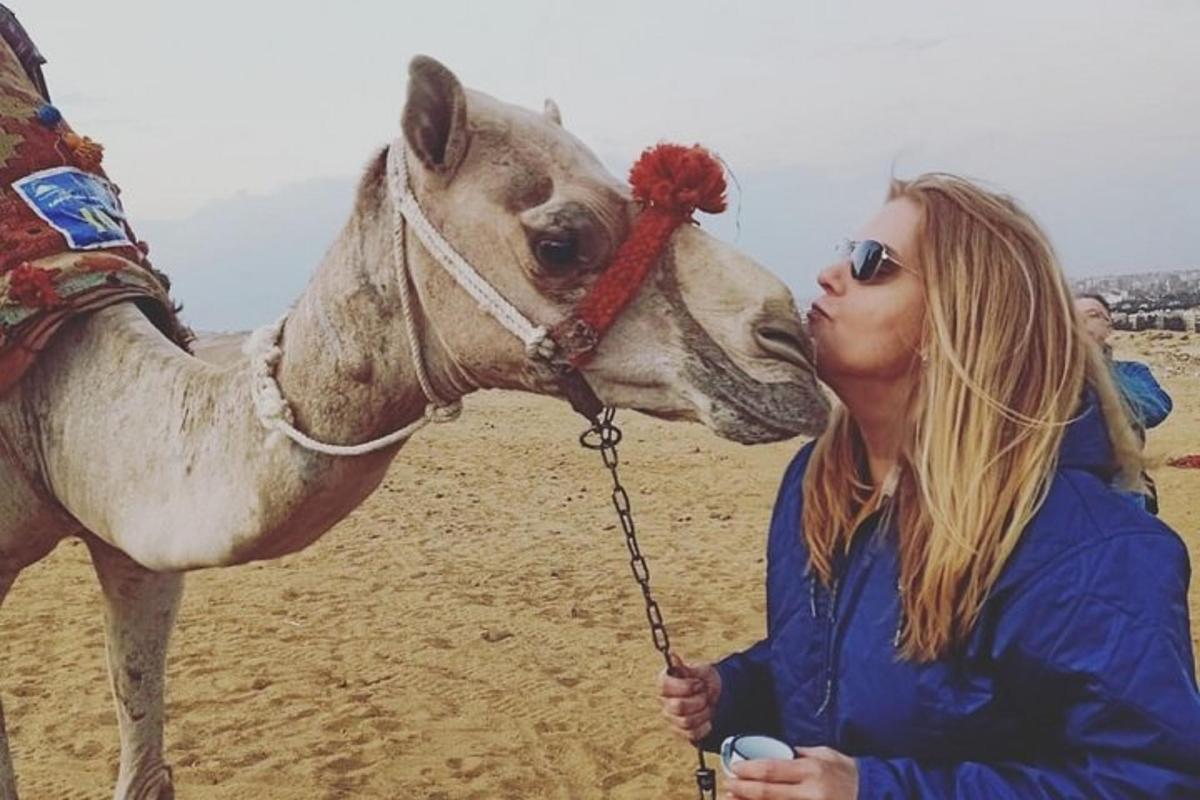 egy nő megcsókol egy tevét a tengerparton
