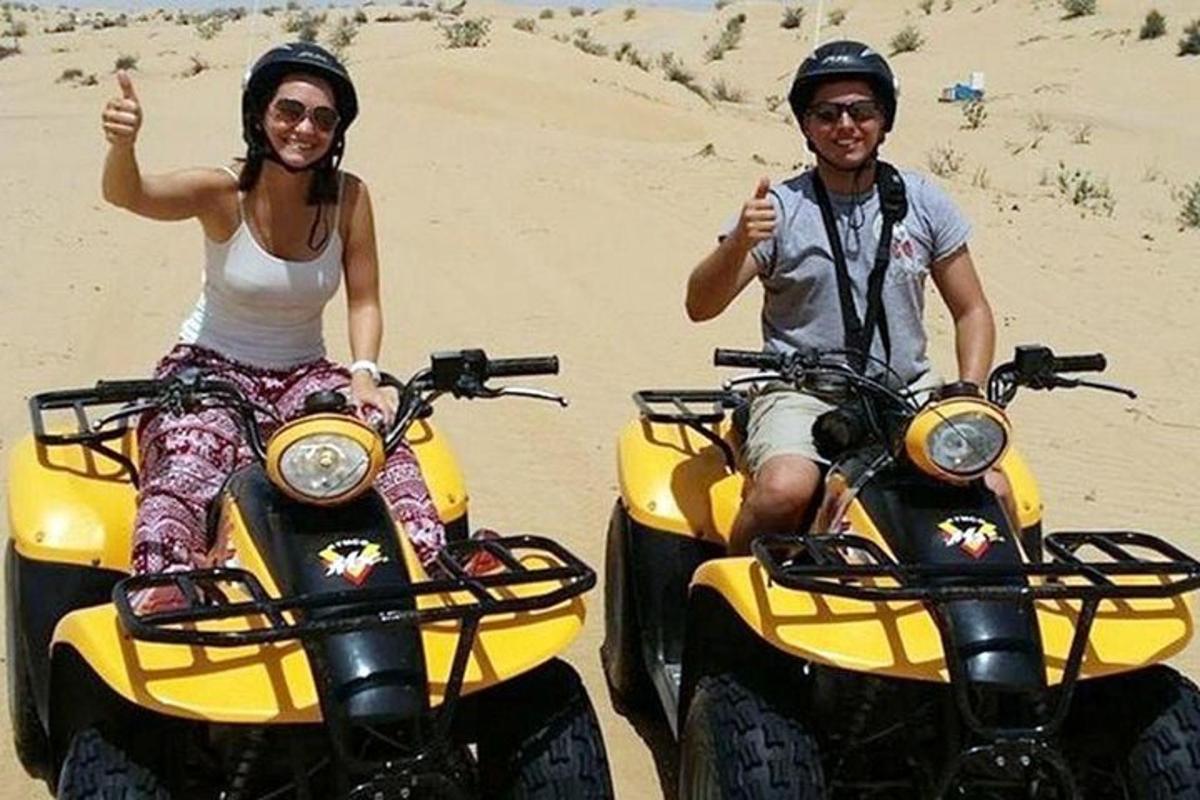 un uomo e una donna seduti su quad nella sabbia