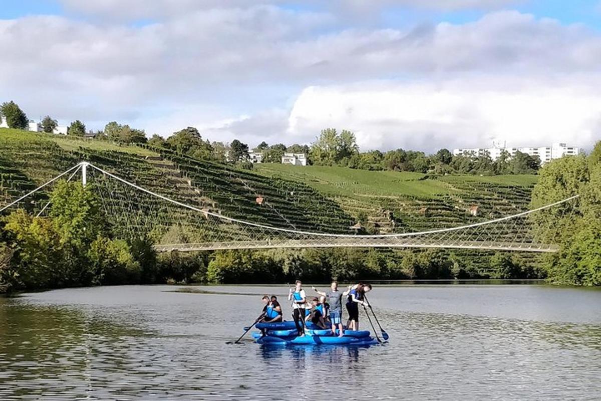 a group of people in boats on a river with a suspension bridge