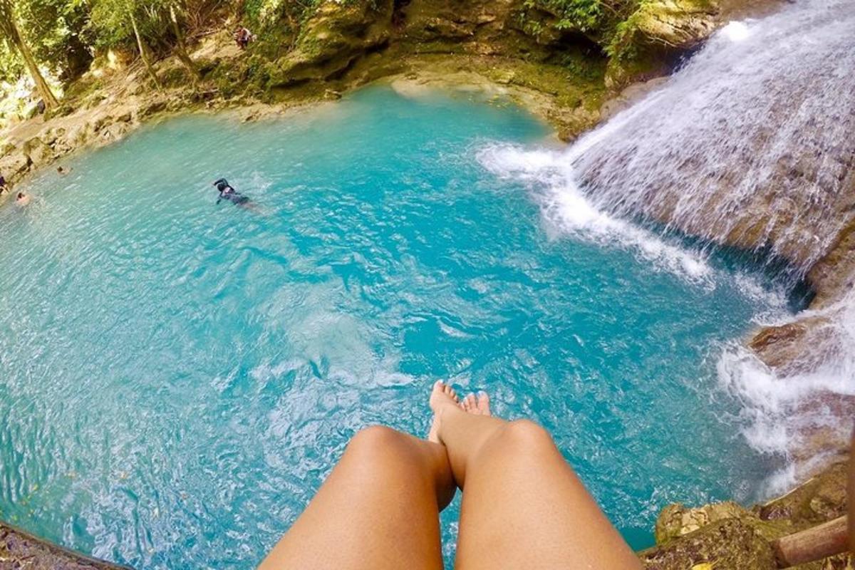 una persona seduta in una pozza d'acqua accanto a una cascata