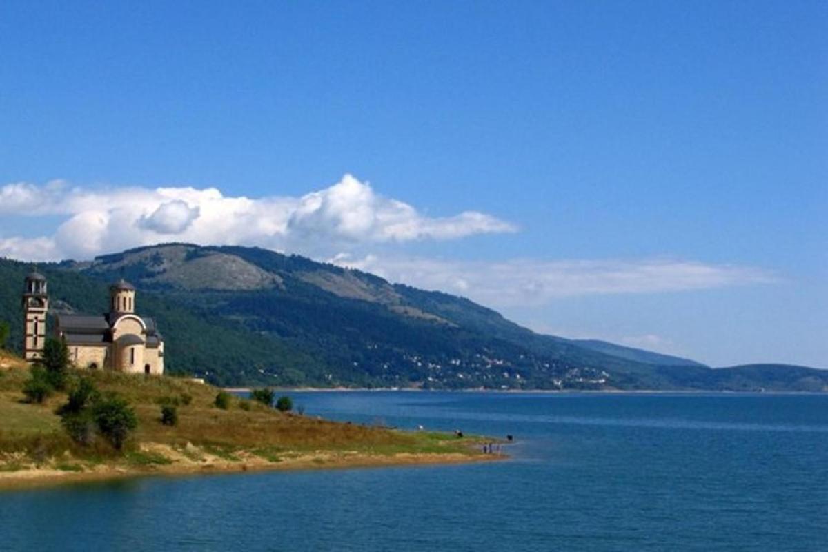 a building on a hill next to a large body of water