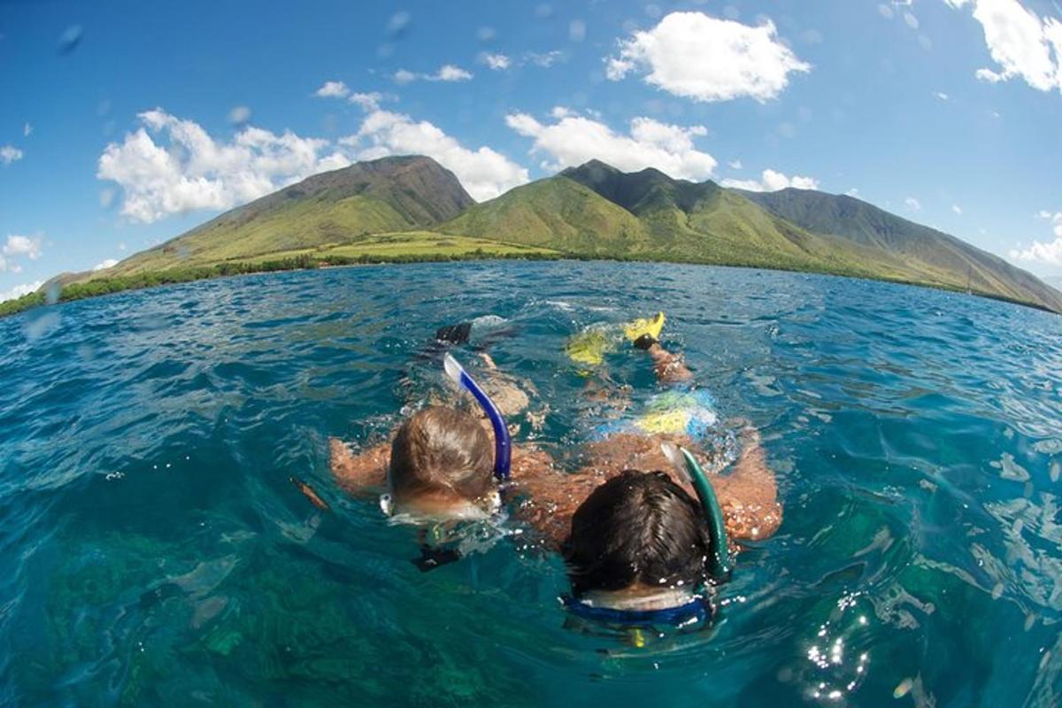 two people floating in the water in front of a island