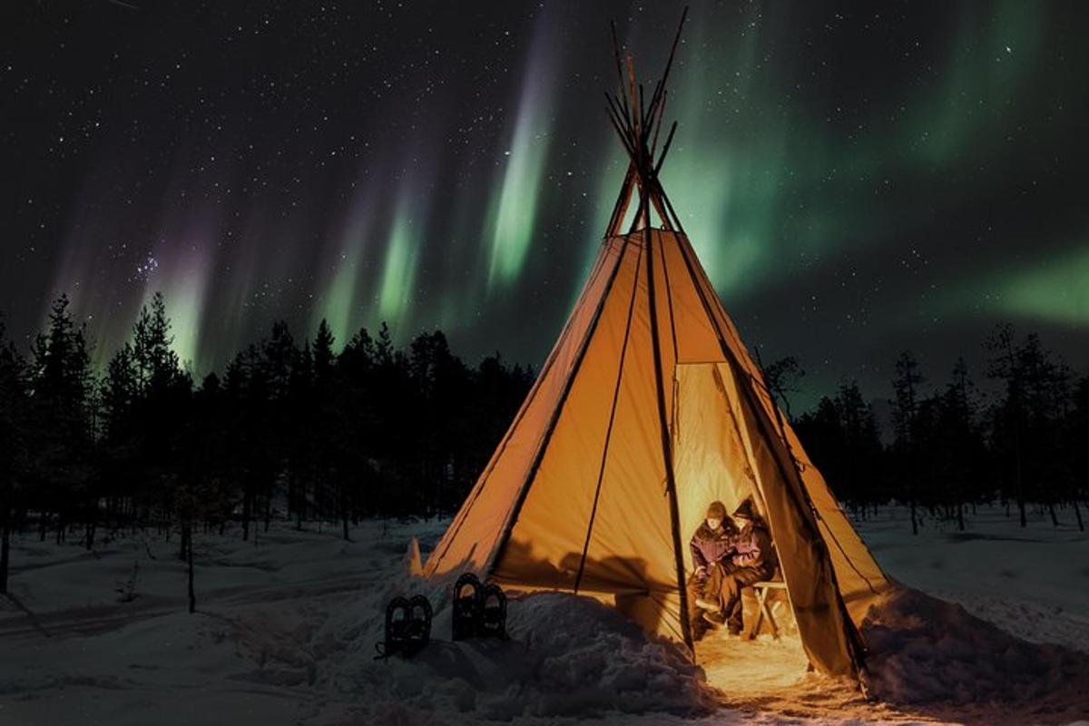 hópur fólks í tjaldi undir norðurljósum
