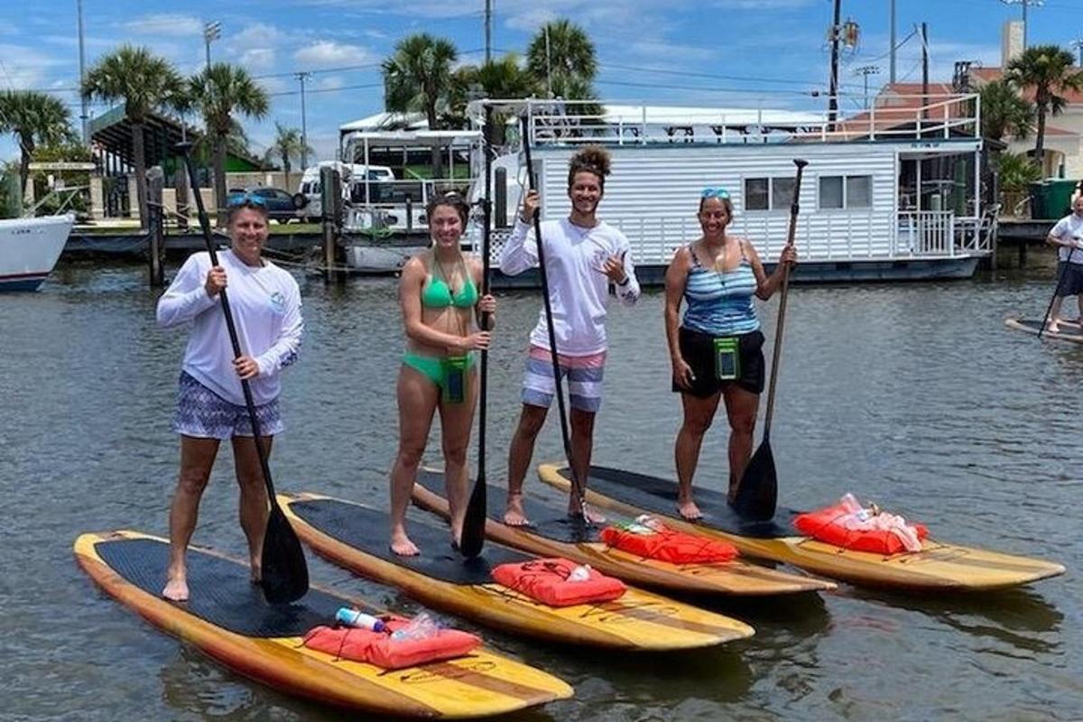 skupina lidí stojících na paddleboardech ve vodě