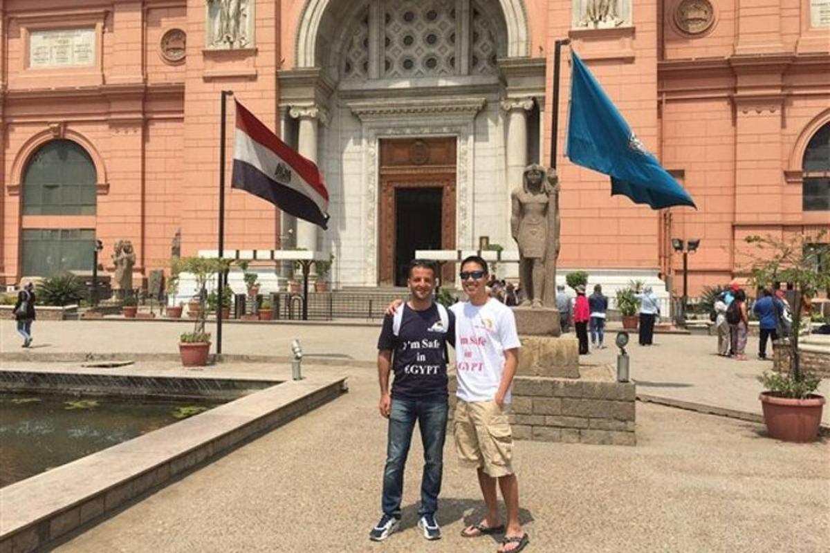 dua lelaki berdiri di hadapan sebuah bangunan dengan bendera