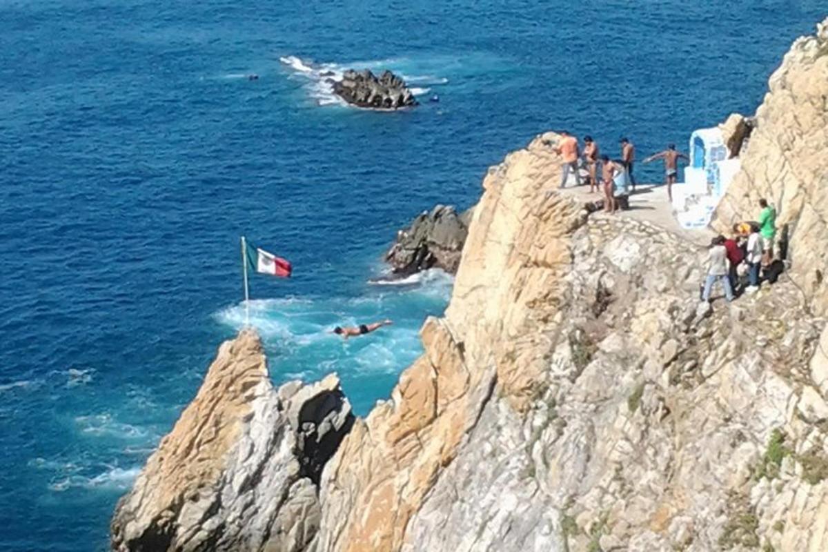 a group of people on top of a cliff with the ocean