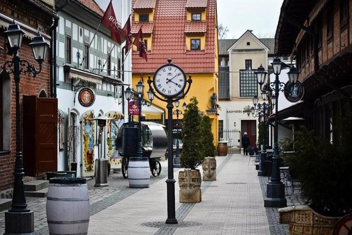 a clock on a pole on a street with buildings