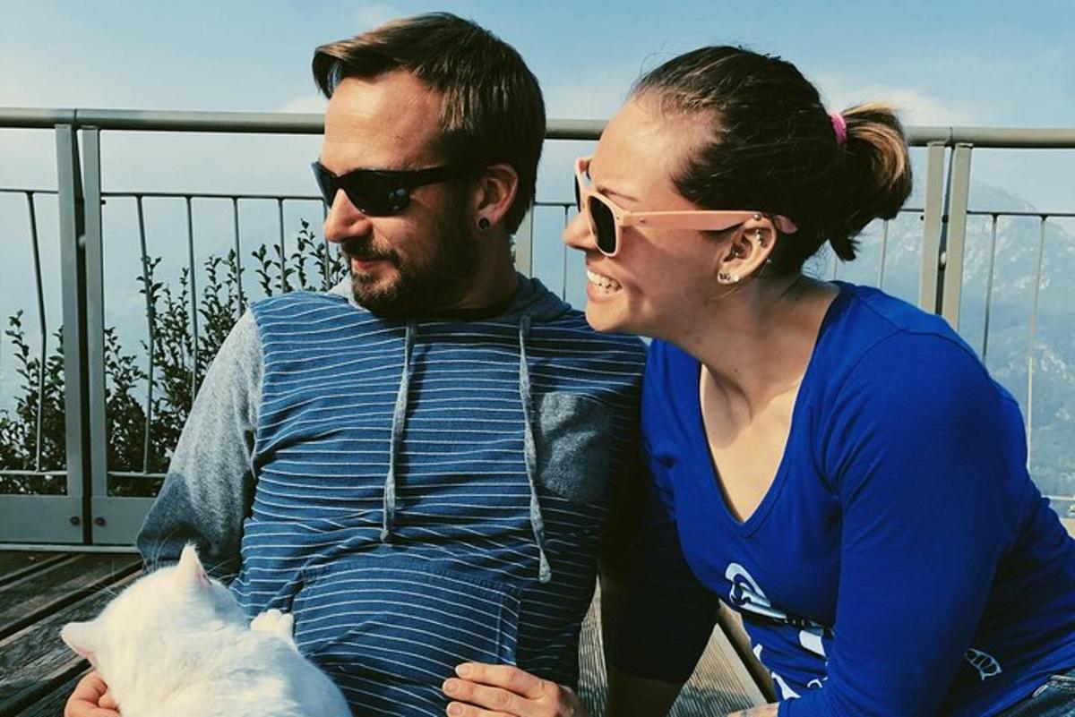 Un hombre y una mujer sentados en un balcón con un gato.