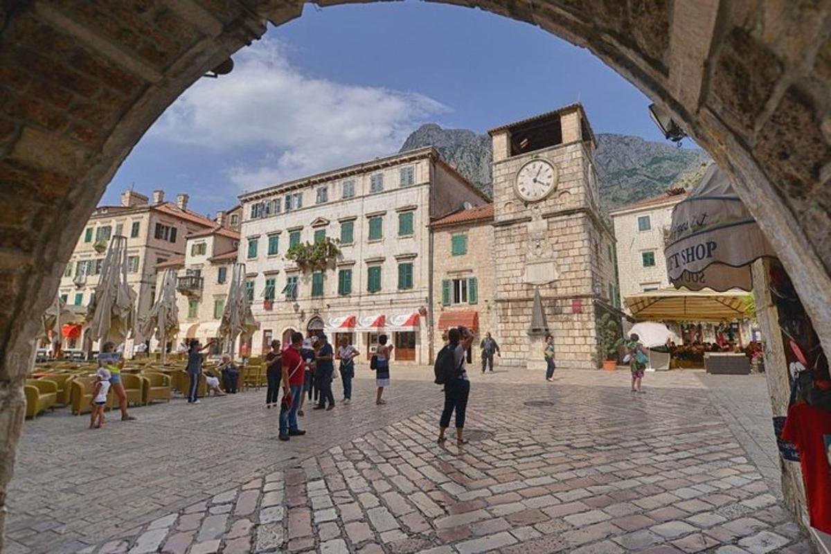 skupina lidí jdoucích po ulici s hodinovou věží