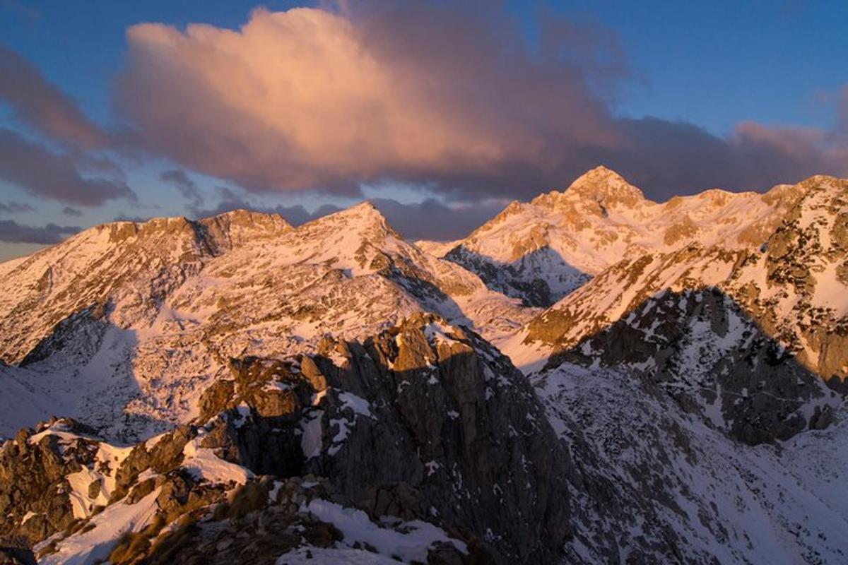 a mountain covered in snow with a cloudy sky