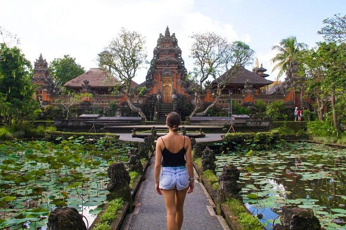 a woman walking in front of a temple with lily pads