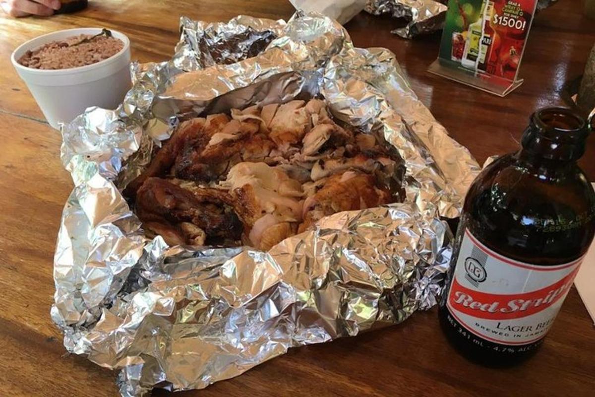 Un pollo envuelto en papel de aluminio junto a una botella de cerveza