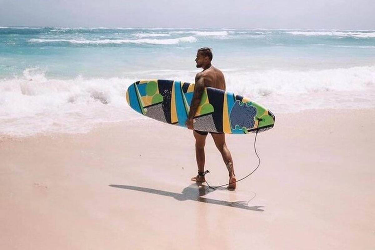 a man standing on the beach holding a surfboard