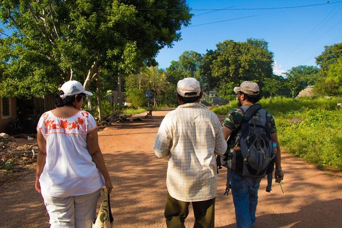 un gruppo di tre persone che camminano lungo una strada sterrata