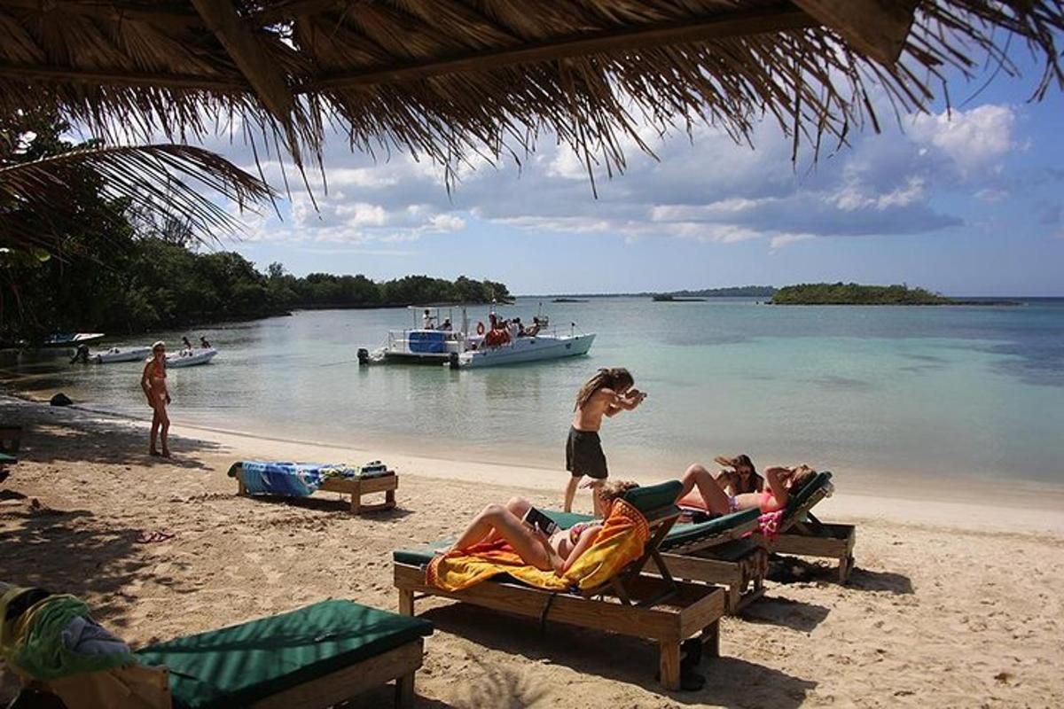 Un grupo de personas tumbadas en una playa con un barco.