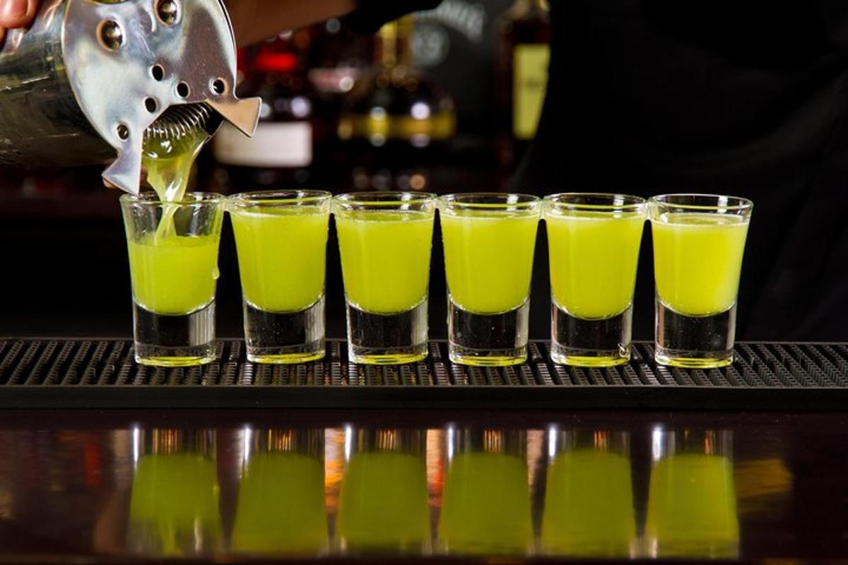 a group of glasses filled with green juice on a bar