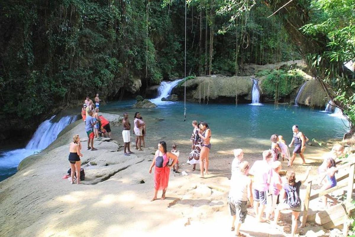 sekumpulan orang berdiri di pantai berhampiran air terjun