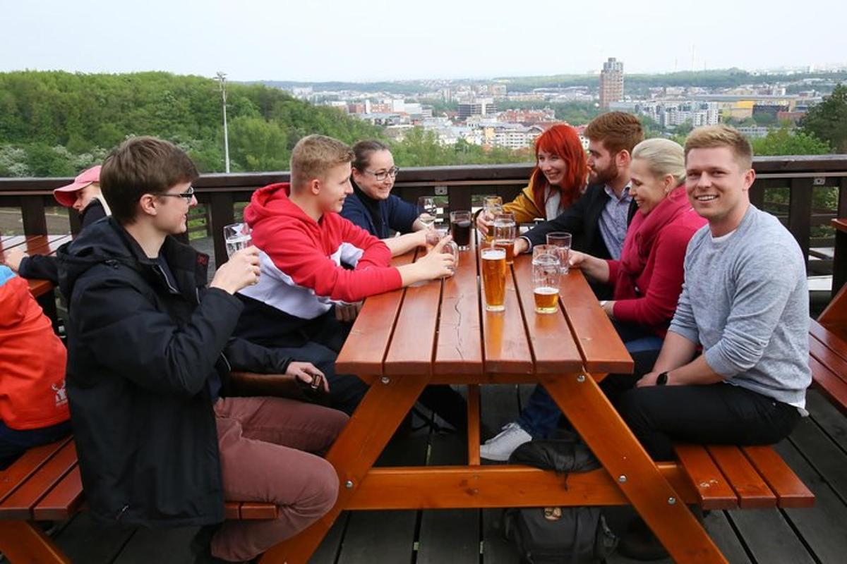 skupina ľudí sediacich okolo stola a pijúcich pivo