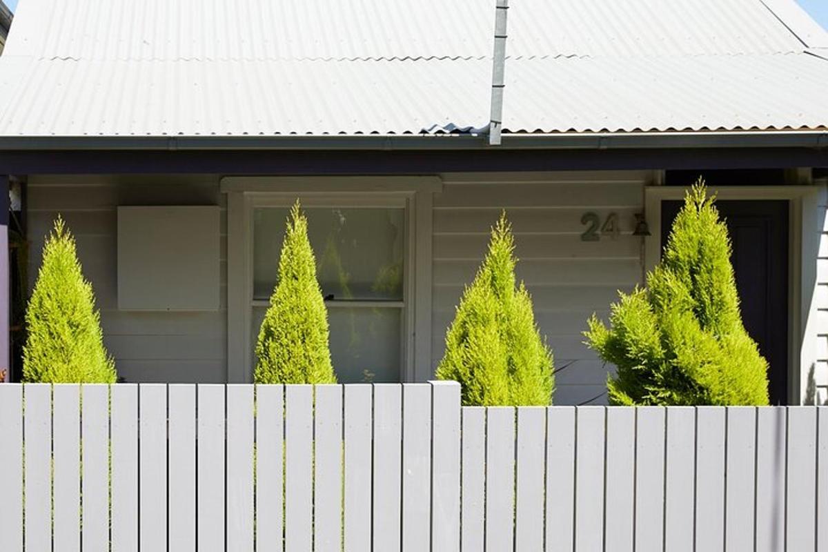 una casa amb una tanca i arbres al davant