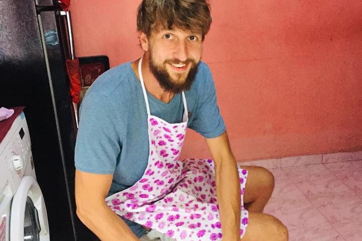 a man in apron sitting on the floor in a kitchen