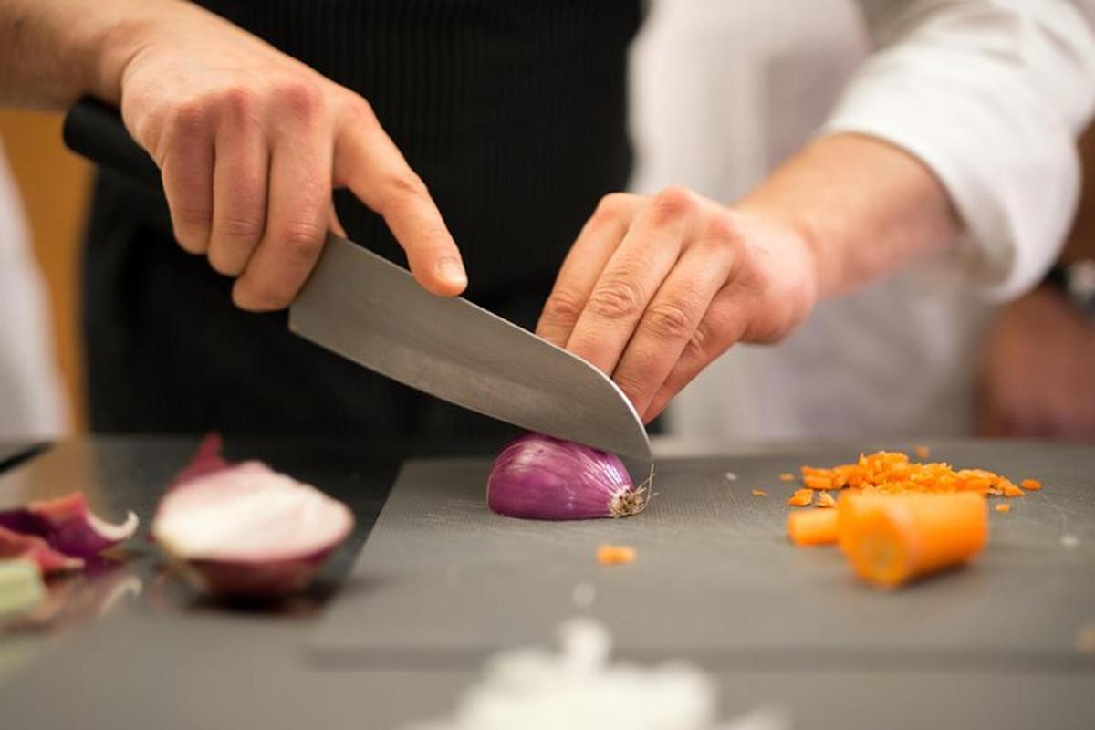 una persona cortando verduras con un cuchillo en un mostrador