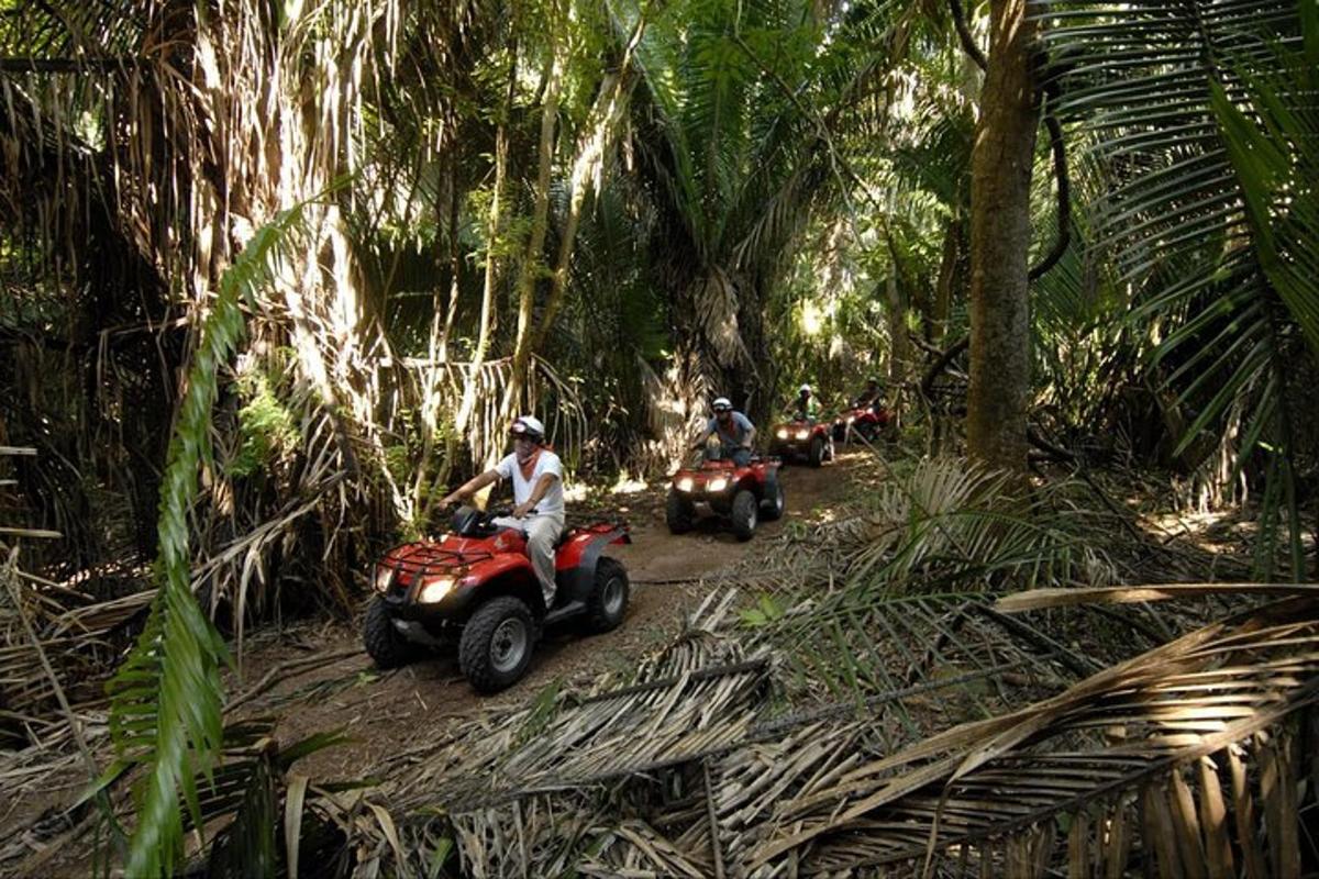 duas pessoas andando de quadriciclo em uma trilha na selva