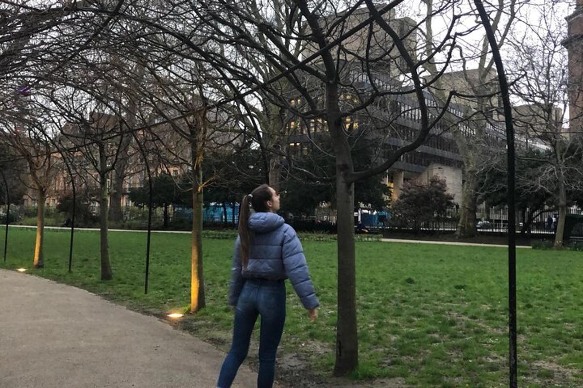 uma mulher parada ao lado de uma árvore em um parque