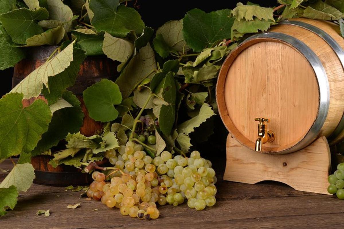 un grappolo d'uva accanto a una botte di vino