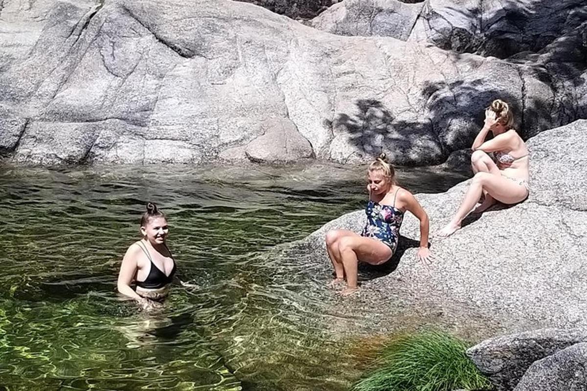 tři ženy sedící na skalách ve vodní ploše