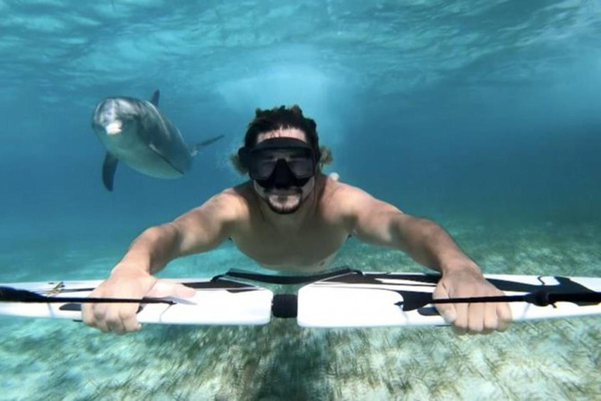 un uomo in acqua con uno squalo sullo sfondo