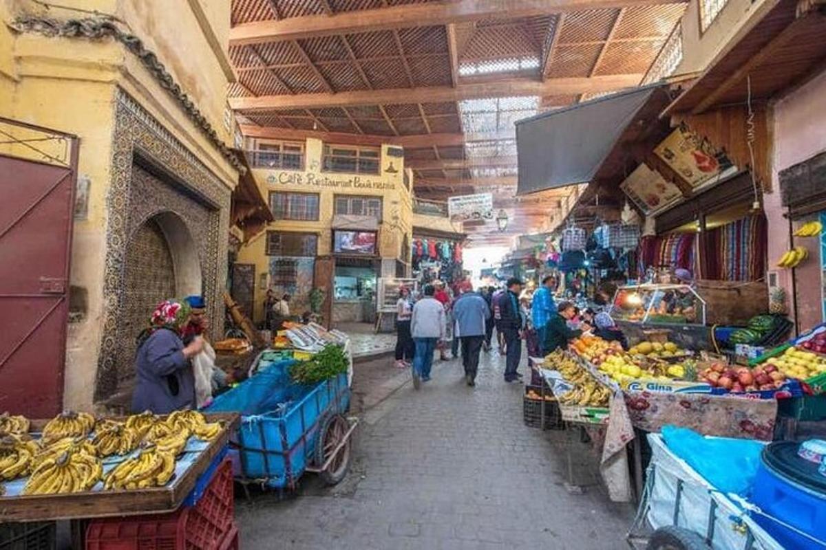 a group of people walking through a market with fruits and vegetables