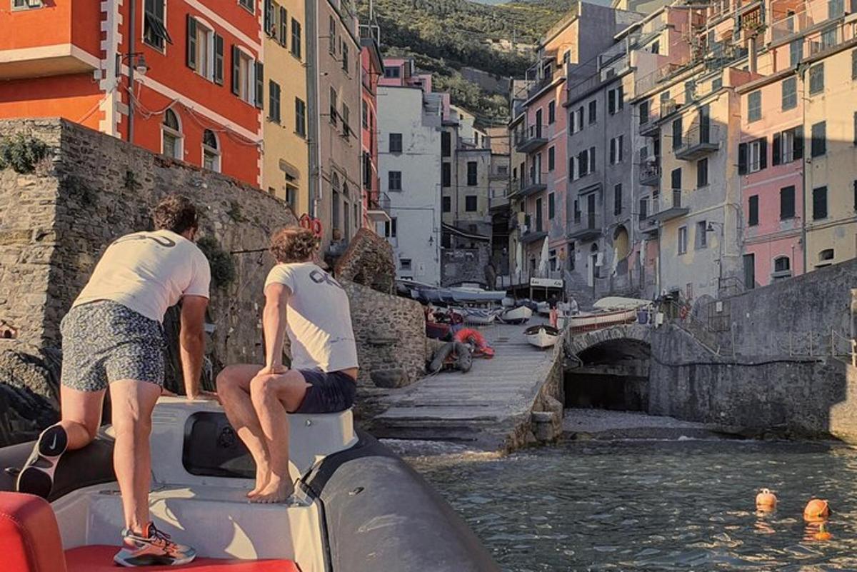 two men standing on the back of a boat in the water