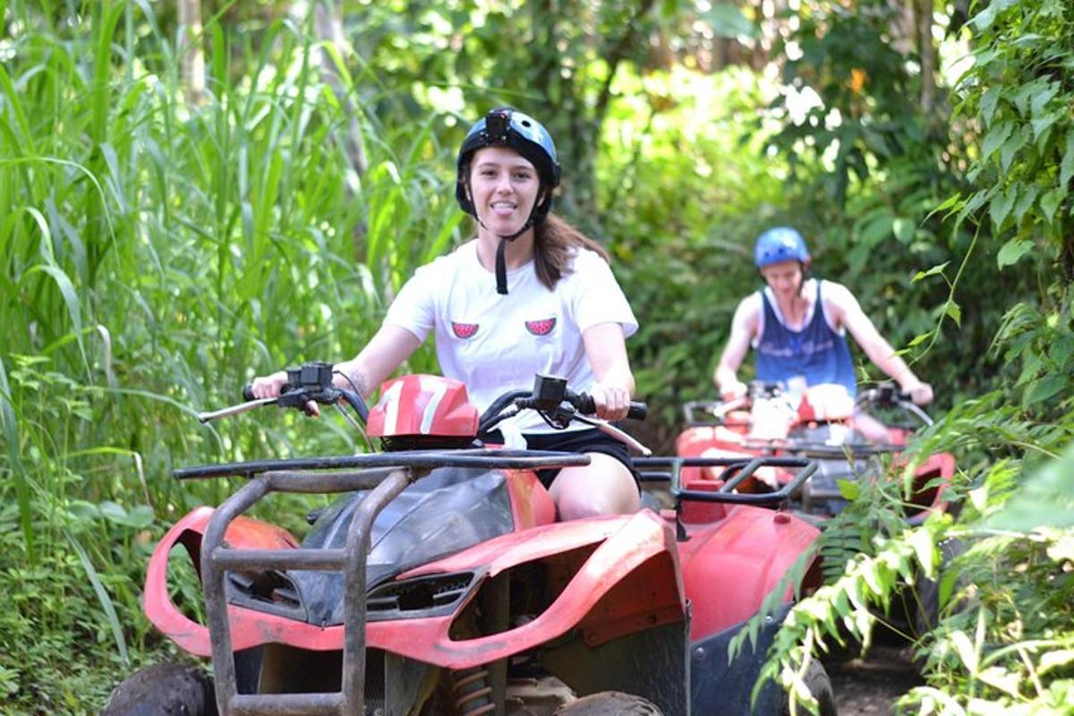 two people riding on four wheelers down a trail