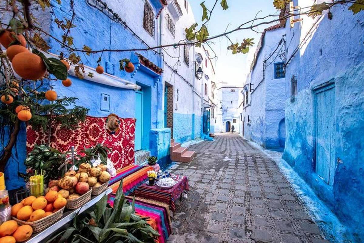 an alley with blue buildings and fruits and vegetables
